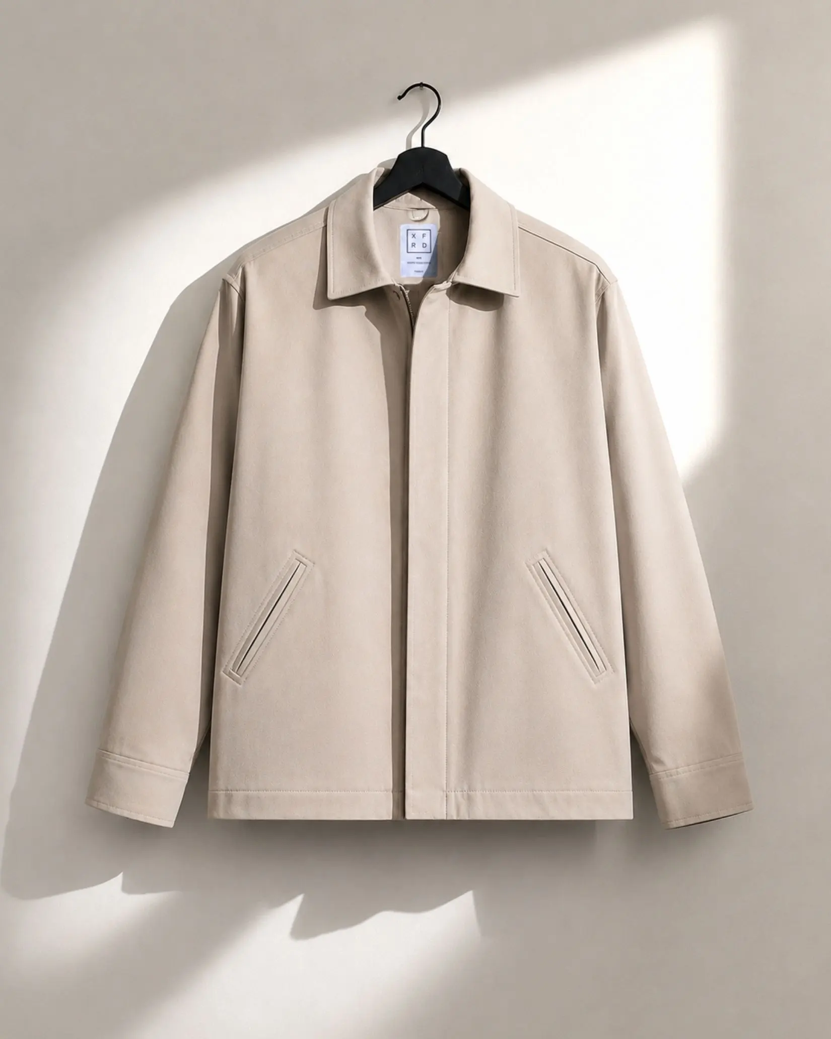 Beige Slate Zip Jacket on a hanger in natural sunlight.